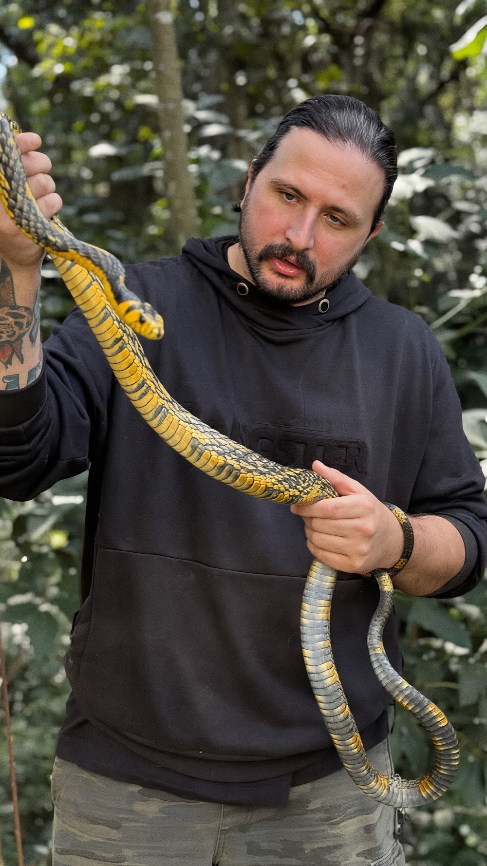 Francisco Dambo segurando uma caninana preta e amarela na mata
