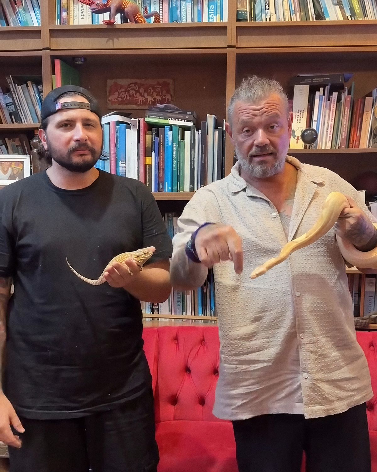 Francisco Dambo e Richard Rasmussen lado a lado na biblioteca da Casa dos Bichos, cada um segurando uma serpente