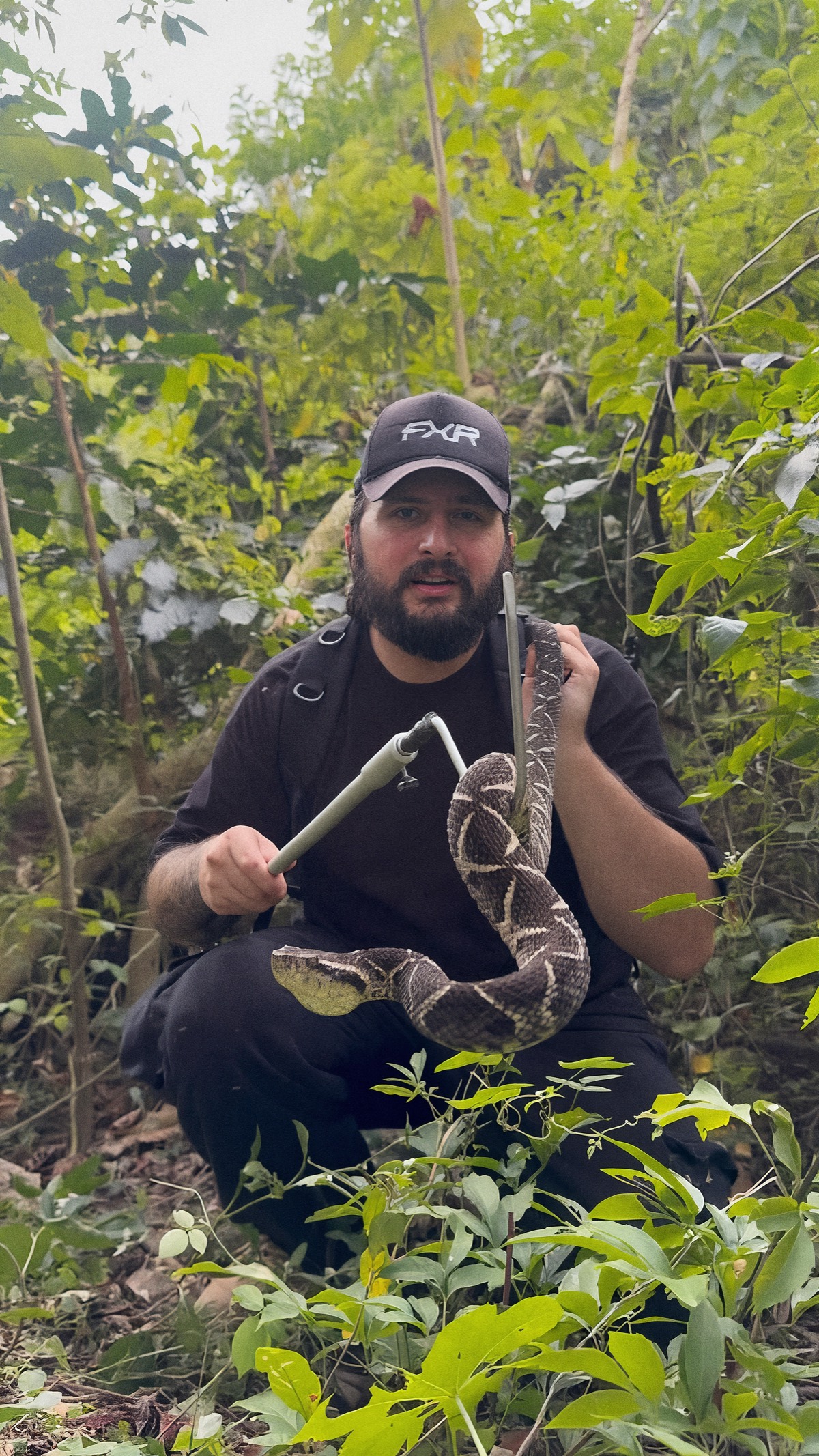 Chico com uma jararacuçu na mata